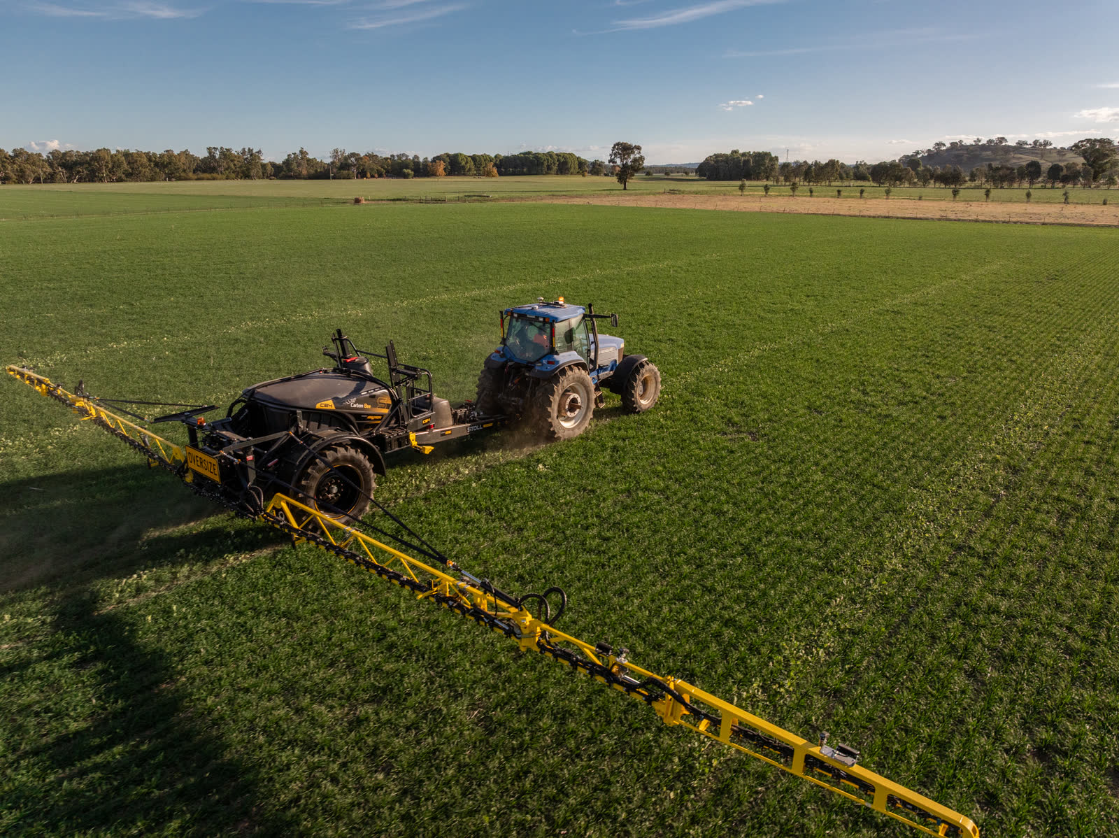 Stoll CB4 and tractor from above, boom spread across the crop