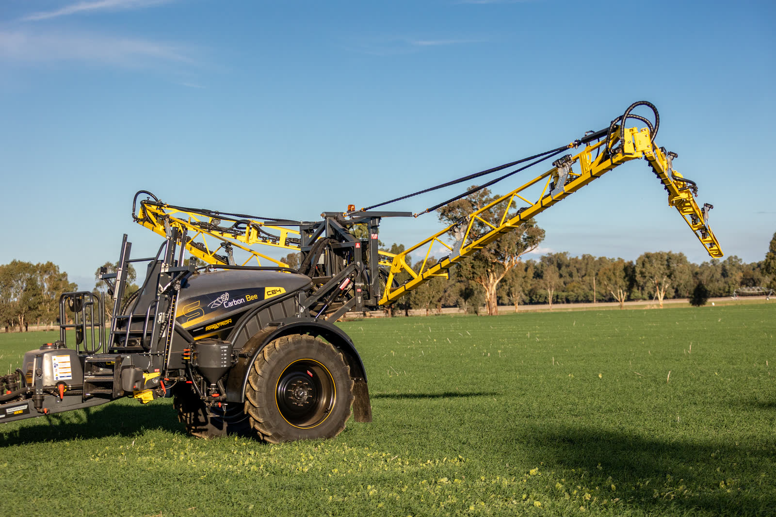 Stoll CB4 with its boom lifting, side on in a green paddock
