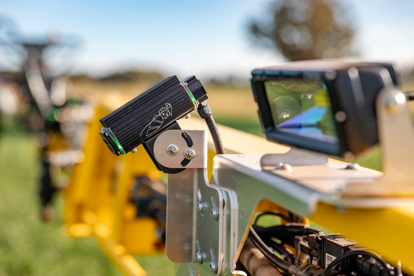 Camera unit and screen mounted on a yellow boom against the sky